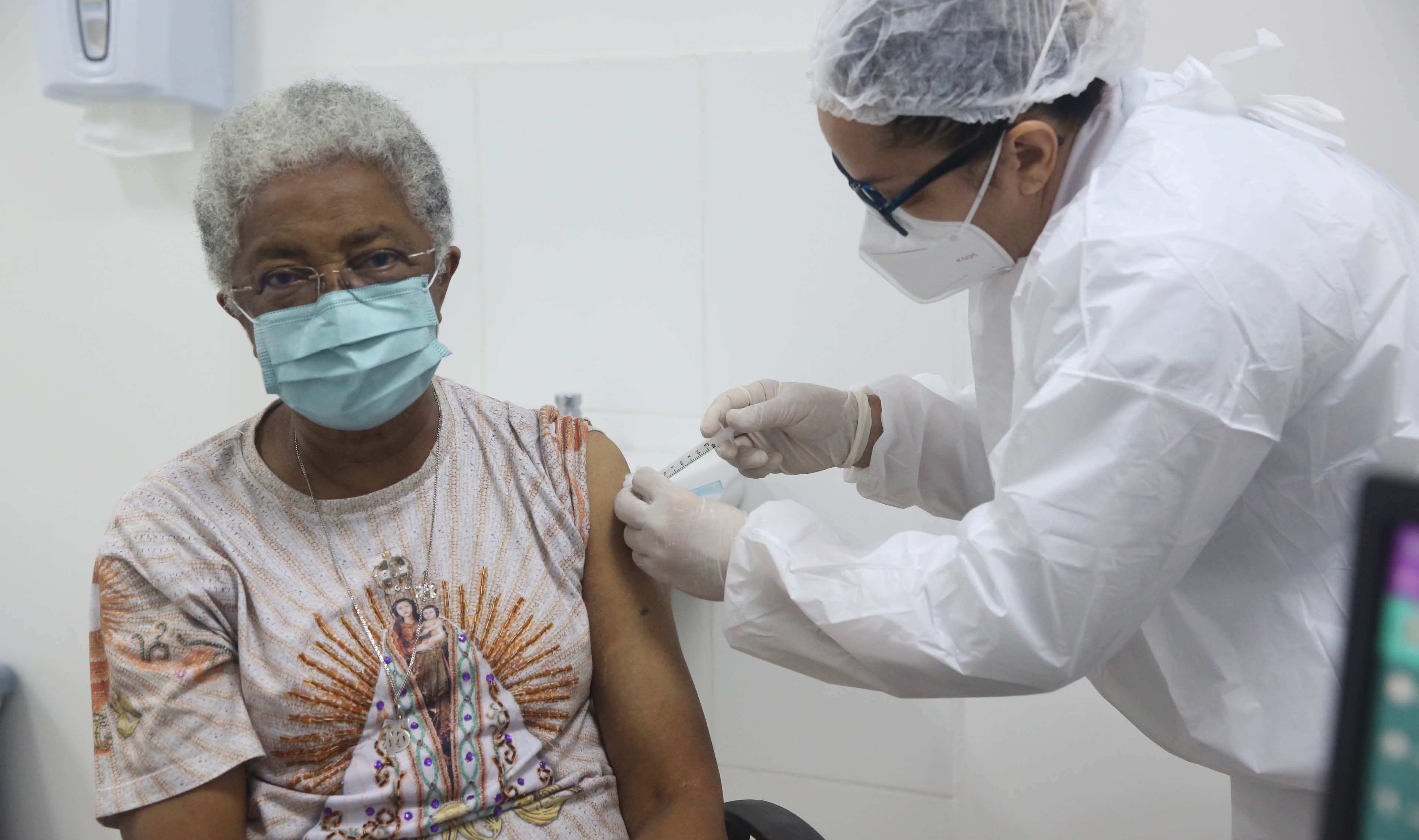 senhora de máscara sendo vacinada